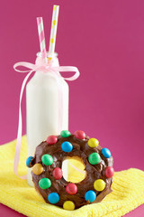 Delicious donut and bottle of milk on color background