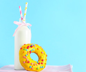 Delicious donut and bottle of milk on color background
