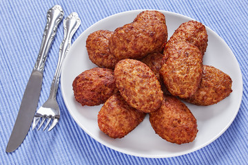 delicious meat cutlets on white plate on table mat