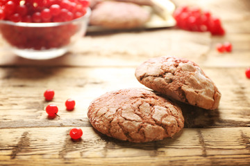 Delicious chocolate cookies and viburnum on rustic wooden table, closeup