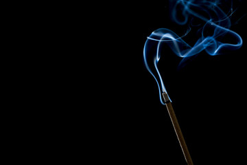 Incense stick with smoke on black background