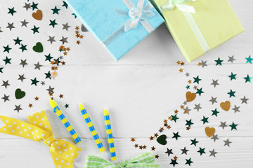 Bright confetti and gift boxes on white wooden background