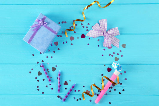 Bright confetti and gift box on blue wooden background