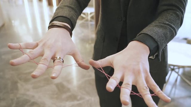 Magician showing trick with clerical gum, hands closeup. illusionist. The man in a suit, interior on background. 
