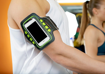 Young man with phone running on treadmill at gym