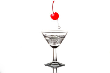 alcohol or soda bubbles in a martini glass with cherry red splashes floats on top