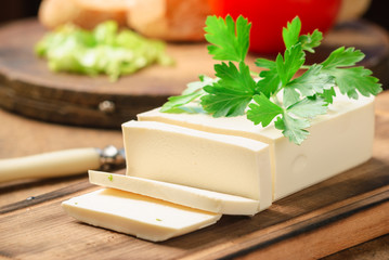 feta cheese on a wooden board decorated with fresh parsley. close up and selective focus. horizontal image