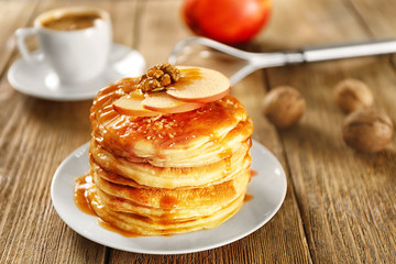 Delicious pancakes with maple syrup and sliced apple on wooden table