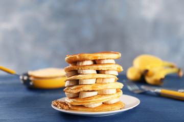 Delicious pancakes with banana and caramel on blue wooden table
