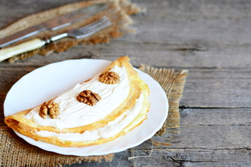 Cottage cheese omelette on a white plate. Delicious omelette stuffed with cottage cheese and walnuts. Vintage wooden background with copy space for text