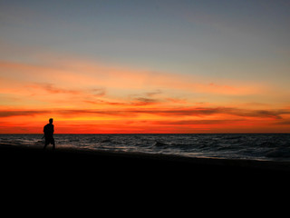 Fototapeta premium Silhouette man walking on sunset beach
