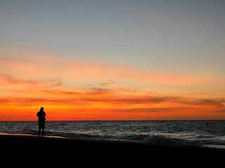 Silhouette man taking photo on sunset beach