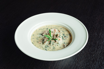 Cream soup with dill in a white plate on a wooden table