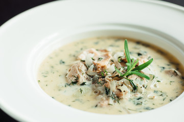 Cream soup with dill in a white plate on a wooden table