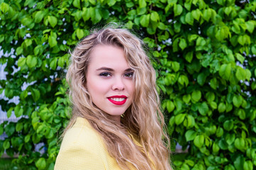 Fototapeta premium Attractive blonde in yellow coat emotionally posing at park