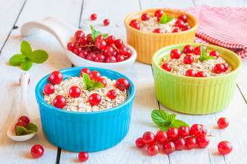 Oat flakes with red currant in colorful bowls