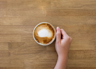 Woman hands holding a cup of coffee with latte art in a brown cu