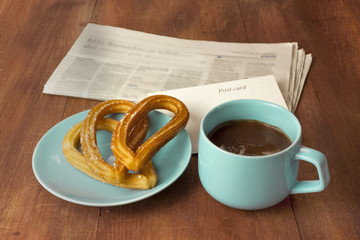 Spanish churros, chocolate, blurred newspaper, postcard
