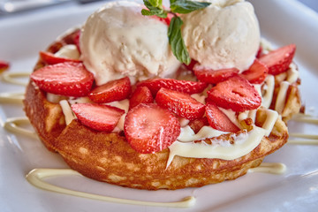 waffles with white chocolate sauce, ice cream and strawberries
