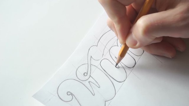Lettering or logo creating with a pencil on white paper. Handlettering design. Designer drawing letters with pen. Sketch artwork. Calligraphy work.