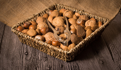 delicious assortment of nuts in a woven basket on wooden backgro