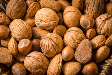 delicious assortment of nuts in a woven basket on wooden backgro