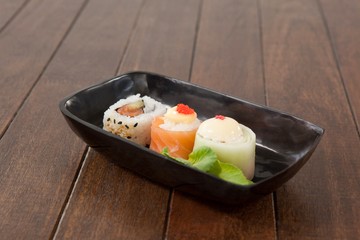 Nigiri and uramaki sushi served on black boat plate