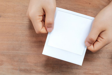 Obraz premium Hand holding a blank photo frame in front of wooden background.