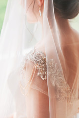 Beautiful charming bride in a luxurious dress looking up.Portrait Of Happy Bride Sitting in wedding dress in a white photo Studio. Young attractive bride with flowers