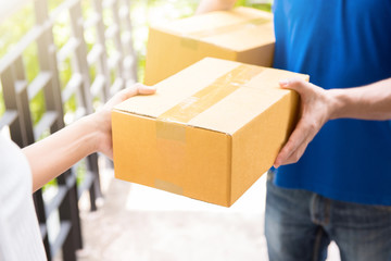 Delivery man in blue uniform handing parcel box to recipient 