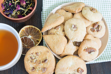 Cookies with nuts spread out on a saucer and a cup of tea for breakfast