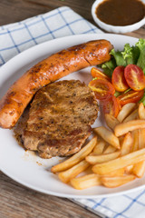 Roasted beef meat steak and sausage with french fries.