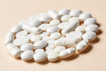 Fototapeta na wymiar white pills on beige background