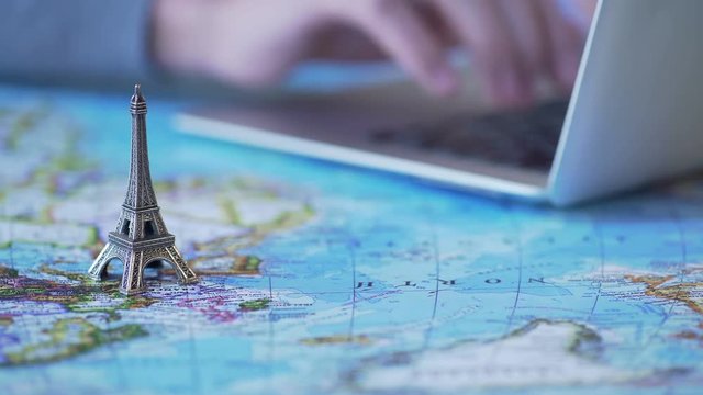Person planning romantic trip to Paris, booking tickets and hotel on laptop