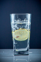 Glass glass of water with lemon on the isolated background. Mountain ineralnaya pure mountain water with gas bubbles and a lemon slice and spray tonic refreshing sports drink.