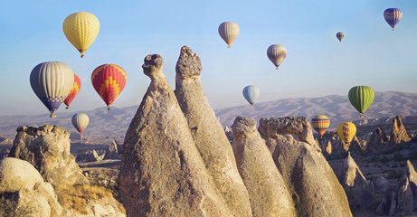 Colorful hot air balloons flying over the valley at Cappadocia, Turkey. Volcanic mountains in...