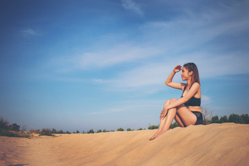 Fototapeta na wymiar Beach holidays woman enjoying summer sun sitting in sand looking