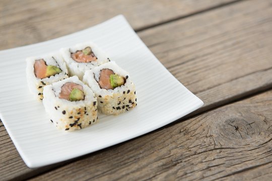 Uramaki sushi served on plate against wooden background