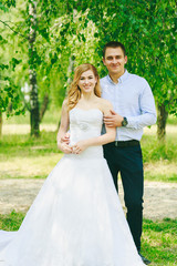 Just married loving hipster couple in wedding dress and suit on green field in a forest at sunset. happy bride and groom walking running and dancing in the summer meadow. Romantic Married young family