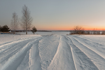 Fototapeta na wymiar snowy road in winter village at dawn.
