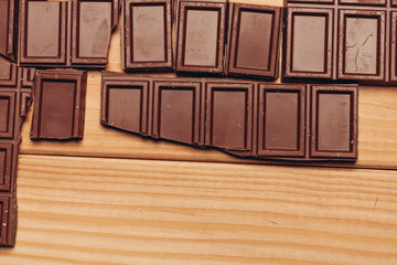 broken chocolate tile on a wooden background, brown