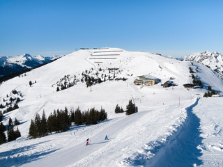 Obraz premium Downhill slope and apres ski mountain hut with restaurant terrace in Saalbach Hinterglemm Leogang winter resort, Tirol, Austria, Europe. Sunny day shot.