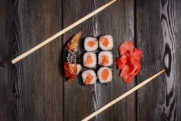 rolls and sushi on a wooden background, chopsticks