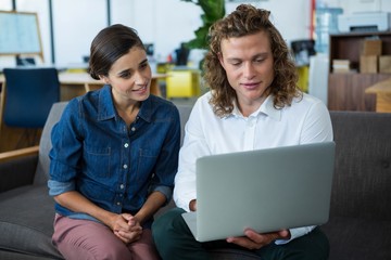Business executives discussing over laptop