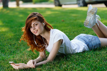 woman with headphones lying on grass, music lover