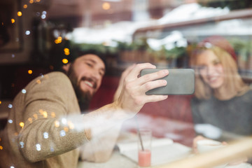 Portrait of funny couple in cafe behind the glass