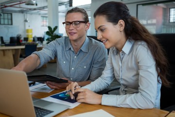 Business executives discussing over laptop