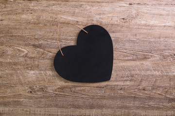 Black heart with rope on wood rustic background. Concept for romantic love. Valentines day design. Wooden grunge board.