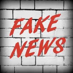 The words Fake News in red text on a white brick wall as a reminder to be aware of hoaxes and disinformation for propaganda uses