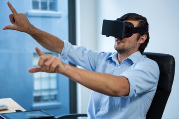Naklejka na ściany i meble Businessman using virtual reality headset at desk